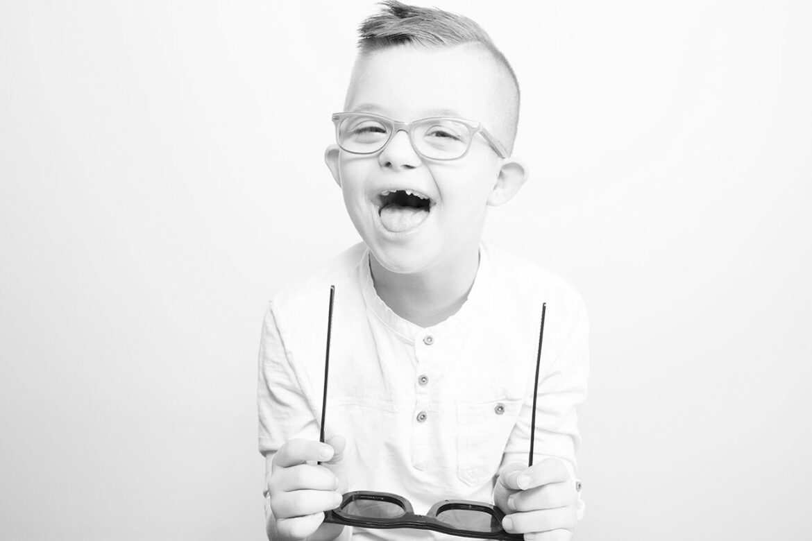 A boy laughs as he tries on glasses to help identify  colour blindness.
