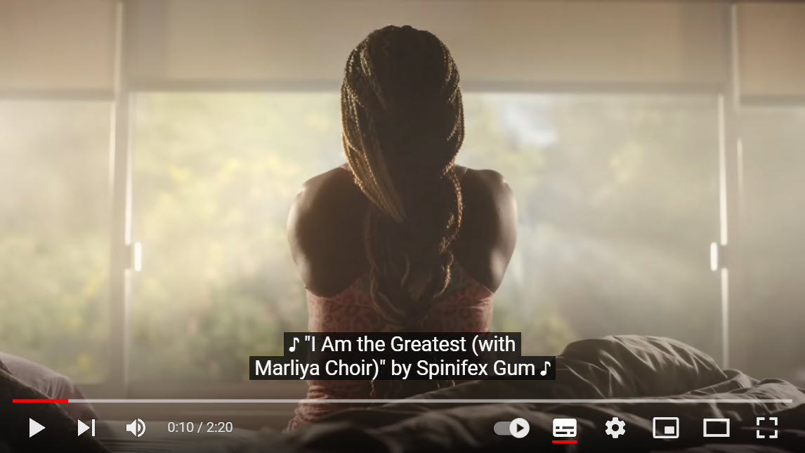 A still from the Apple Greatest video showing a woman with a limb difference sitting in bed.
